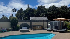 A swimming pool with lounge chairs and a hot tub. - Academy Motor Inn (Tauranga)