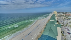A coastal hotel with a beach view, a parking lot, and a high-rise building in the background. - Tower 3-102 Long Beach Resort. Free Beach Chair Service! (Panama City Beach)