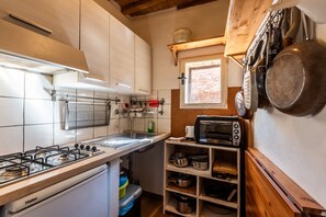 A compact kitchen with a gas stove, a built-in oven, and a microwave. - Apartment 'In The Medieval Village' with Wi-Fi and Air Conditioning (Belforte - Radicondoli)