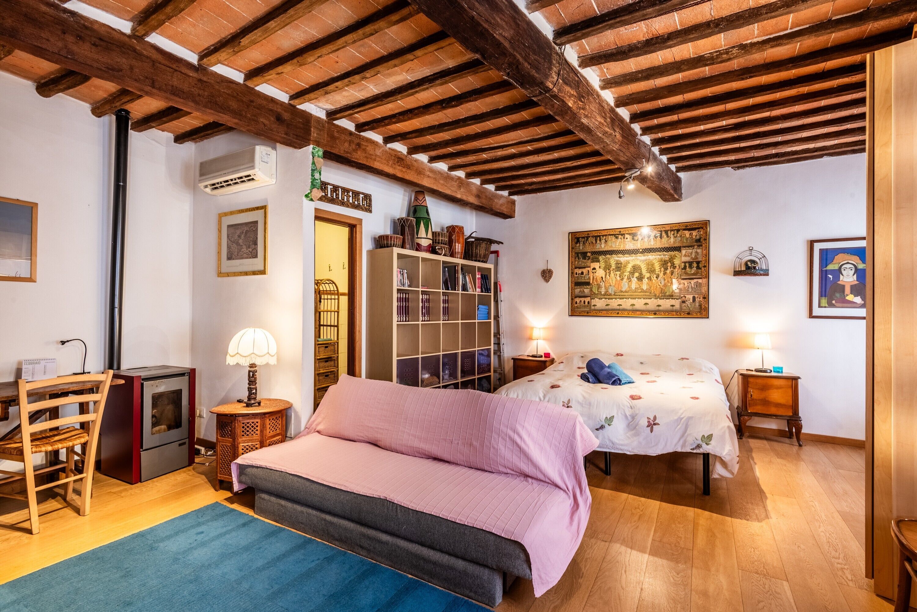 Ein gemütliches Zimmer mit einem Bett, einem Schreibtisch, einem Bücherregal und einer Holzzahl.