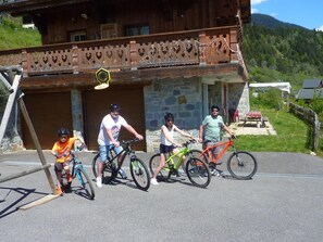 Cyclists gather in front of this mountain lodge, offering a scenic backdrop for outdoor adventures.