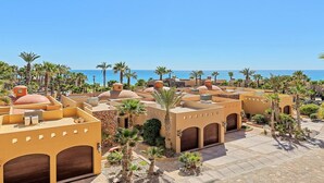 Een resort met meerdere gebouwen, palmbomen en een helder uitzicht op de zee.
