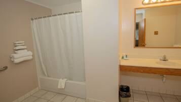 A bathroom with a bathtub, a vanity with a mirror, and a sink.