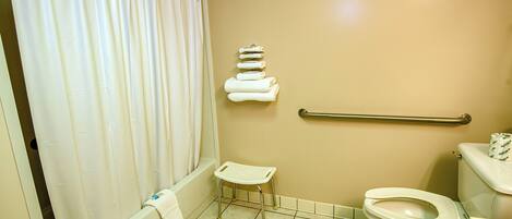 Un baño con bañera, inodoro y un pequeño taburete.