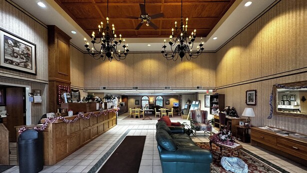 A spacious lobby with a reception desk, seating area, and a ceiling fan. - Westgate Inn (Coudersport)
