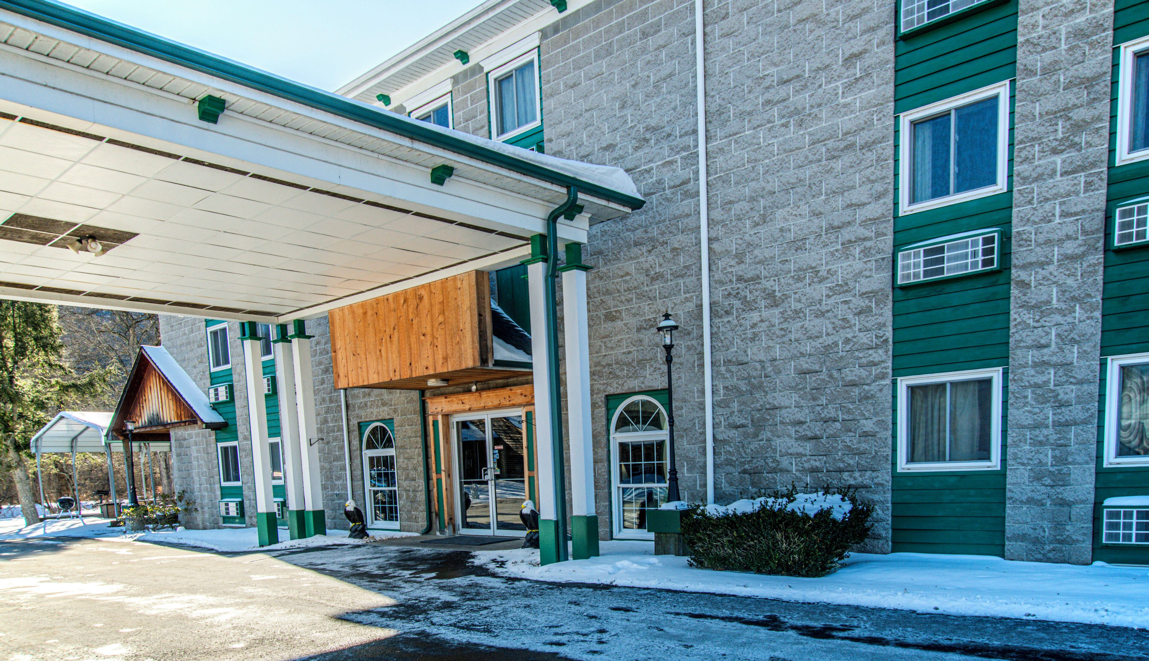 A building with a covered entrance, stone facade, and multiple windows.