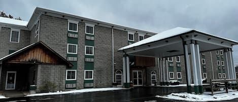 A multi-story building with a covered entrance and a handicap parking sign.