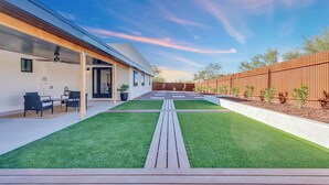Une maison moderne dotée d’un patio, d’une terrasse en bois et d’une pelouse bien entretenue.