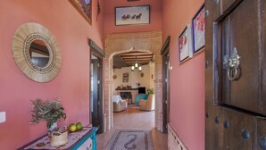 Un pasillo que conduce a una sala de estar con chimenea, un espejo y un banco con una planta.