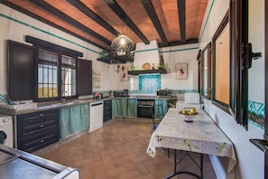 Une cuisine avec une table dressée pour le repas, un lave-linge et un luminaire suspendu.