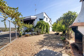 Un quartier résidentiel avec une maison blanche, une allée gravillonnée et un jardin clos.