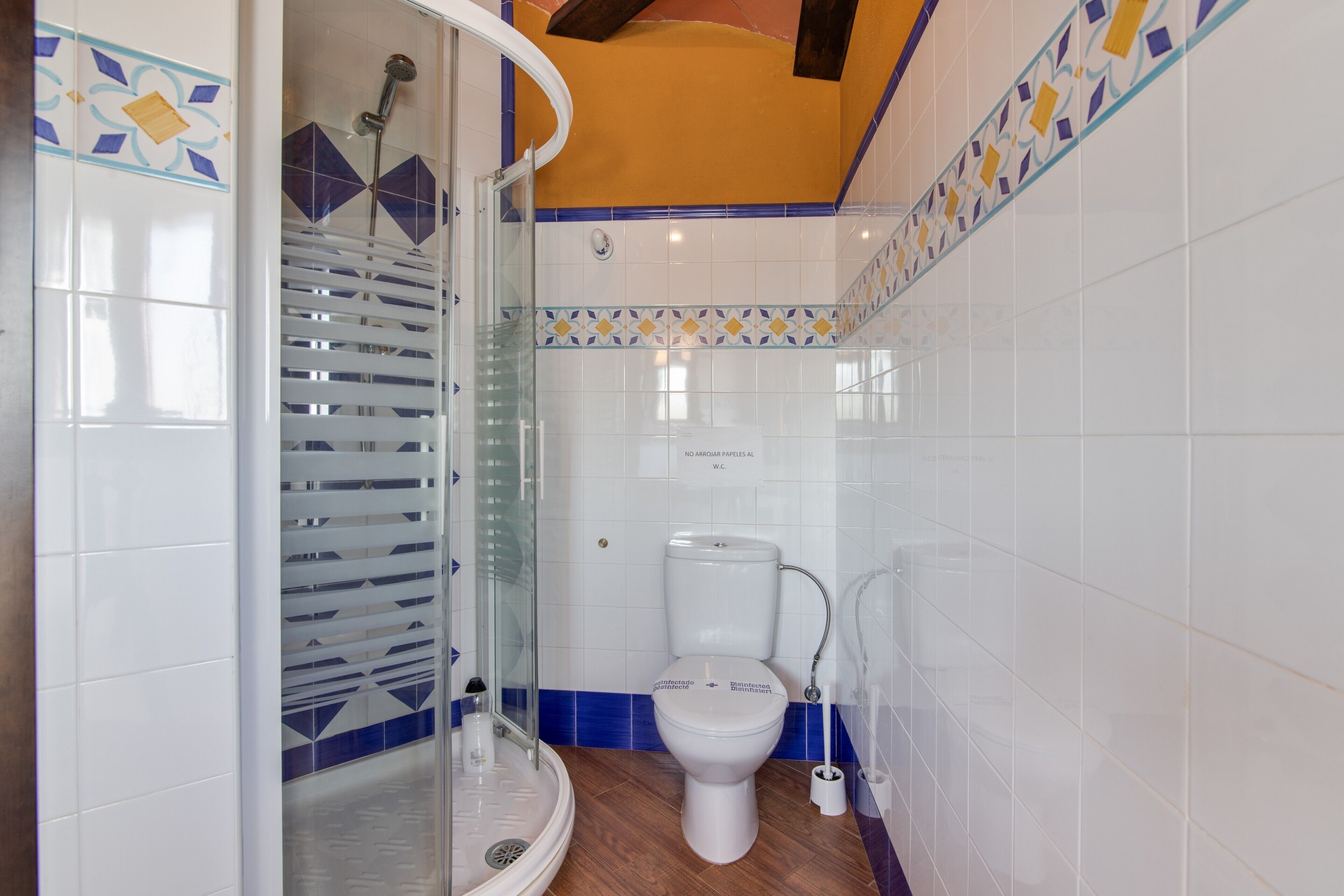 Un baño con ducha, inodoro y cabina de ducha con paredes de vidrio.