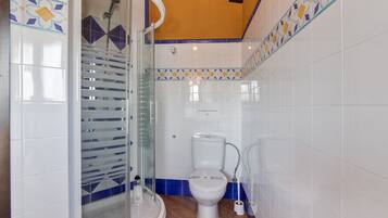 Un baño con ducha, inodoro y cabina de ducha con paredes de vidrio.
