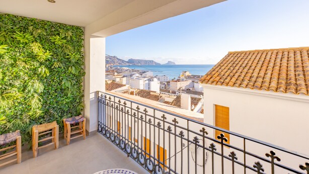 A balcony with a green wall, a railing, and a view of buildings and the sea. - Holiday Home 'Mimar Altea Remedi' with Sea View, Wi-Fi and Air Conditioning (Altea)