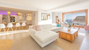 A modern living room with a white sectional sofa, a wooden coffee table, and a dining area with white chairs. - Holiday Home 'Mimar Altea Remedi' with Sea View, Wi-Fi and Air Conditioning (Altea)