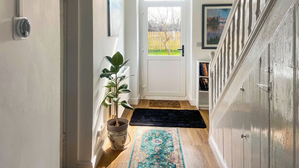 A hallway with a potted plant, a rug, a door with a view, and a staircase. - Ddwylig Isaf Farmhouse - UK48624 (Rhyl and Prestatyn)
