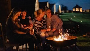 Four people sitting around a campfire at night. - Ensuite Wooden Cabin in Rural Staffordshire (Tamworth)