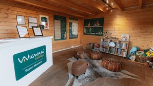 A reception area with a wooden interior, a reception desk labeled 'WIGWAM holidays Saxon Meadow', and informational posters on the walls. - Ensuite Wooden Cabin in Rural Staffordshire (Tamworth)