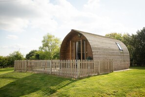 A wooden, semi-circular building with a sloped roof, surrounded by a wooden fence. - Ensuite Wooden Cabin in Rural Staffordshire (Tamworth)