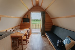 A cozy, wooden interior with a dining area, a sofa, and a TV. - Ensuite Wooden Cabin in Rural Staffordshire (Tamworth)