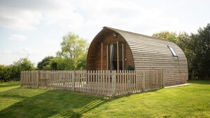 A wooden, semi-circular building with a sloped roof, surrounded by a wooden fence. - Ensuite Wooden Cabin in Rural Staffordshire (Tamworth)