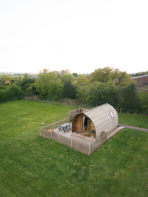 Una estructura en forma de cúpula de madera con una terraza y una mesa de picnic en un campo cubierto de hierba.