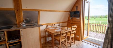 A compact kitchen with wooden cabinets, a sink, and a dining table with chairs.