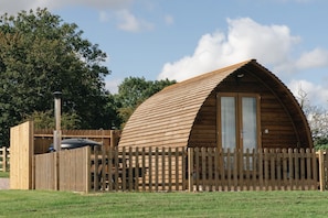 A wooden cabin with a sloped roof, a fenced exterior, and a visible door. - Ensuite Wooden Cabin With Hot Tub (Tamworth)