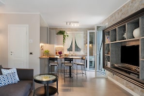 Un salon moderne avec un canapé, une table basse ronde et un téléviseur fixé au mur, qui est en pierre.