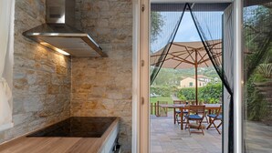 A stone wall kitchen with a built-in oven and a view of an outdoor patio with a table and chairs. - Terraced House 'Due Ulivi' with Private Terrace, Garden, and Wi-Fi (Lavagna)