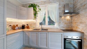 A kitchen with white cabinetry, a built-in oven, a stainless steel range hood, a window with curtains, and a plant on the counter. - Terraced House 'Due Ulivi' with Private Terrace, Garden, and Wi-Fi (Lavagna)