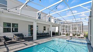 Une piscine dotée d’une structure en verre, de mobilier d’extérieur et d’un espace patio.