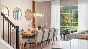 Un espace de salle à manger moderne avec une table en bois, des chaises à revêtement gris et un lustre.