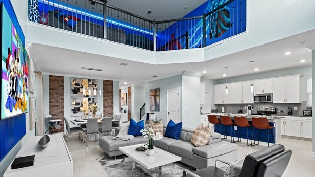 A modern, open-plan living area with a dining area, kitchen, and a balcony with a railing. - Ultimate Disney House | Pool+Hot Tub | Game Room (Davenport)