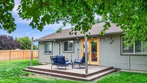 Einbungalow mit einer überdachten Terrasse, auf der zwei blaue Stühle stehen.