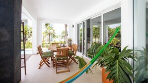 Un patio espacioso con una mesa de comedor, sillas y una hamaca.