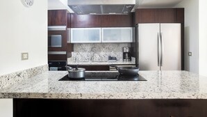 Una cocina moderna con encimeras de granito, electrodomésticos de acero inoxidable y armarios de madera oscura.