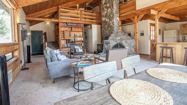 A spacious living area with a stone fireplace, wooden beams, and a cozy seating arrangement.