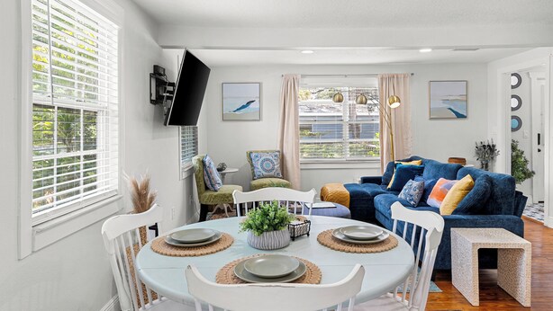 A dining area with a round table set for four, surrounded by white chairs. - Retreat off Main Street (Safety Harbor)