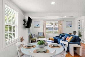 A dining area with a round table set for four, surrounded by white chairs. - Retreat off Main Street (Safety Harbor)