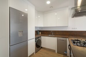 A compact kitchen with a stainless steel refrigerator, a washing machine, a dishwasher, and a gas stove. - Holiday Apartment 'Vivienda en Santa Catalina' with Wi-Fi (Las Palmas de Gran Canaria)