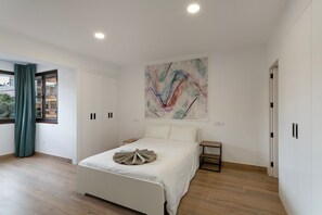 A bedroom with a bed, a nightstand, a wardrobe, and a large abstract painting on the wall. - Holiday Apartment 'Vivienda en Santa Catalina' with Wi-Fi (Las Palmas de Gran Canaria)