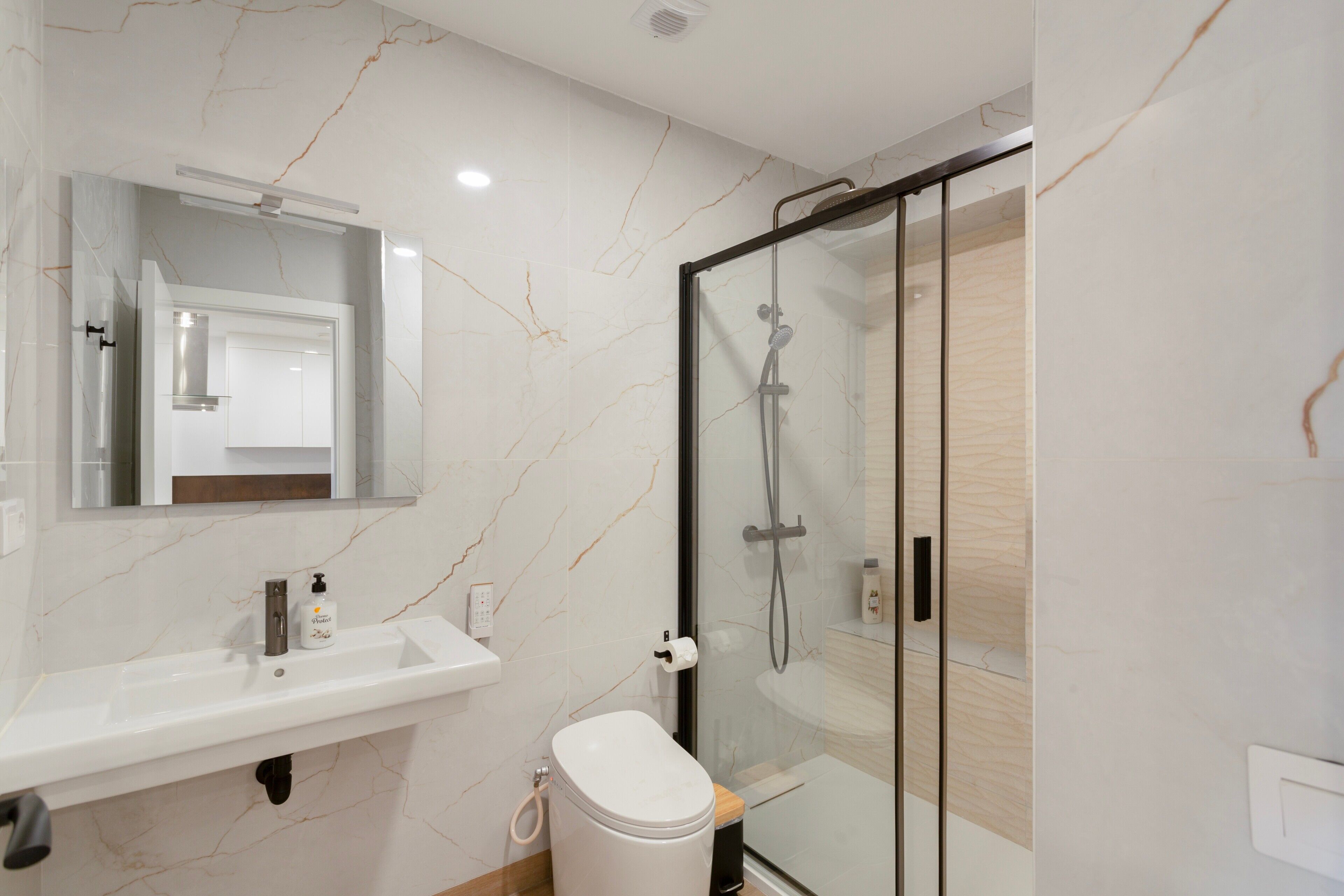 A modern bathroom with a glass shower enclosure, a white sink, and a toilet.