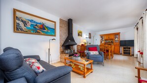 A living room with a sofa, a coffee table, a fireplace, and a dining area with wooden furniture.