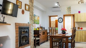 Uma sala de estar com lareira, televisão na parede e um espaço de jantar com mobiliário de madeira.