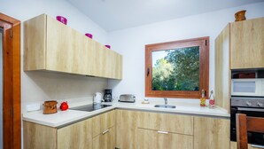 Uma cozinha compacta com armários de madeira, uma janela, uma pia, uma torradeira e um fogão.