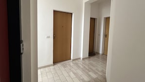 A hallway with white walls, a tiled floor, and wooden doors. - SE131 - Senigallia, two-room apartment with air conditioning and terrace (Senigallia)