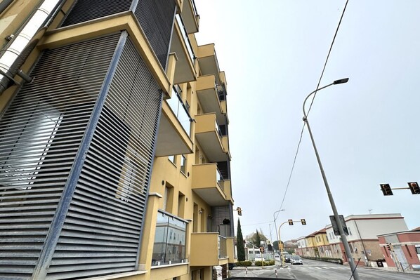 A multi-story building with balconies, a street view, and traffic lights.