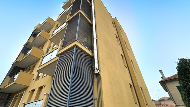 A multi-story building with balconies, a central air conditioning unit, and a clear sky. - SE131 - Senigallia, two-room apartment with air conditioning and terrace (Senigallia)