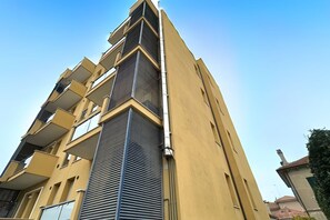 Un immeuble à plusieurs étages doté de balcons, d’un système de climatisation central et surplombant un ciel dégagé.